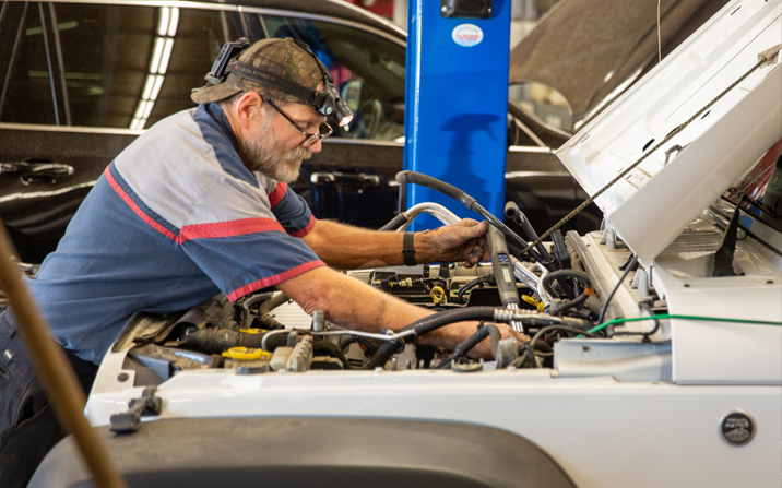 Technician at work under hood of white car | Frank's Auto Service and Repair, Inc.