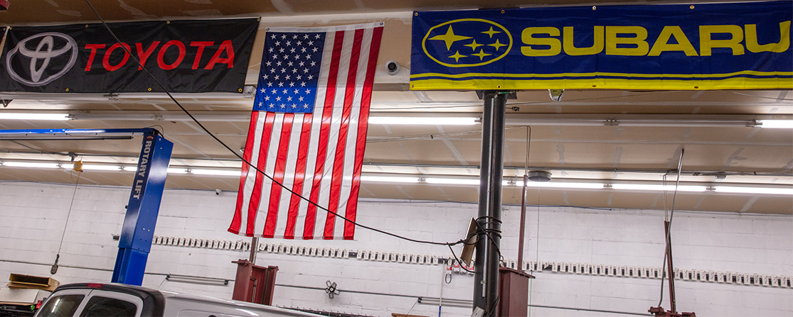 Ceiling of our garage with American flag, Toyota banner, and Subaru banner | Frank's Auto Service and Repair, Inc.